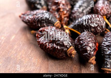 Dried wrinkled briar berries. Dry rose hips. Dog-rose fruits on a rustic wooden surface. Macro. Healthy food concept Stock Photo