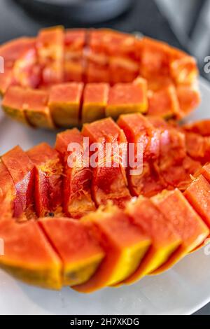 Closeup macro of Caribbean red ripe papaya fruit sliced two halves with fresh orange flesh on slices cut in half vertical view Stock Photo
