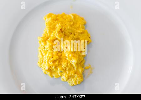 Flat top lay macro closeup of fresh egg scrambled eggs omelette in classic French cooking style on white plate cooked traditional morning breakfast wi Stock Photo