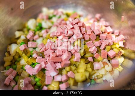 Traditional Ukrainian or Russian salad olivie olivier macro closeup with pickled cucumbers, diced potatoes, carrots, mayonnaise, peas and cubed meat b Stock Photo