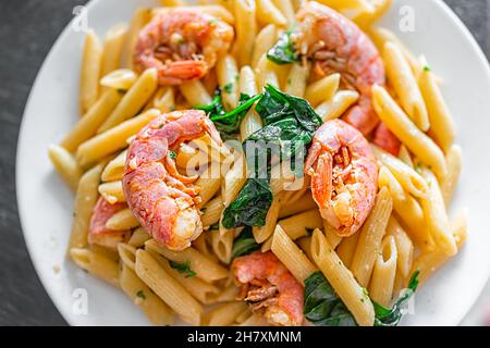 Macro closeup flat lay top view of sauteed cooked whole large king jumbo Argentinian shrimp seafood with penne Italian pasta in olive oil sliced garli Stock Photo