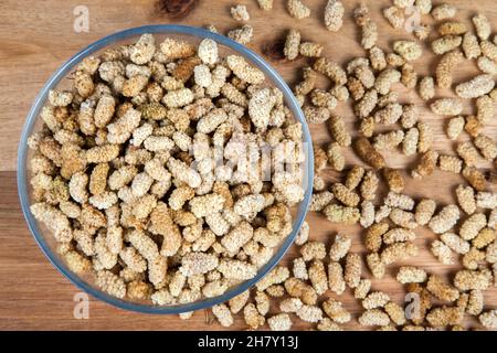 Dried mulberry in glass bowl on wooden background Stock Photo