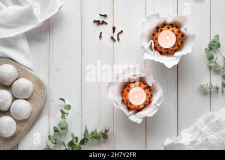Eucalyptus twigs, candles in pomander ball oranges, scissors and gingerbread cookie on cutting board Stock Photo