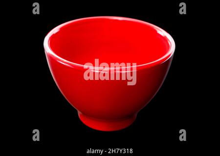 Red ceramic bowl isolated on black lackground. Empty dishware Stock Photo
