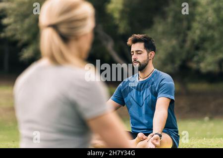 Learner and instructor doing yoga in a park Stock Photo