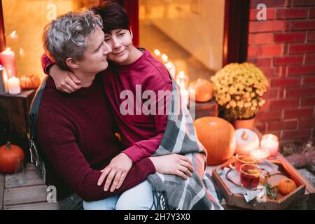 A couple having a romantic date on the porch of their home. Cozy ideas on how to spend time at home. Autumn tea time outdoors on house entrance decora Stock Photo
