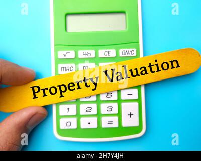 Calculator and hand holding ice cream stick with the word property valuation. Stock Photo