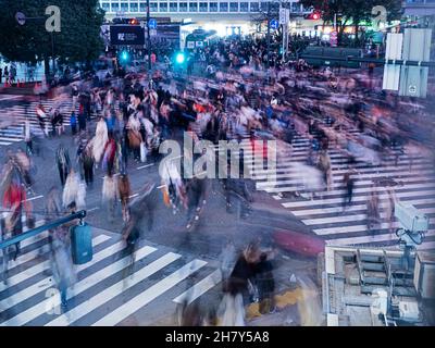 Hundreds of pedestrians rush across the Shibuya Scramble at rush hour when the lights change. Stock Photo
