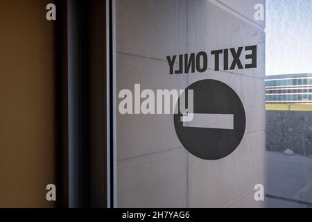 An exit only sign on a glass door.  This building has since been demolished. Stock Photo