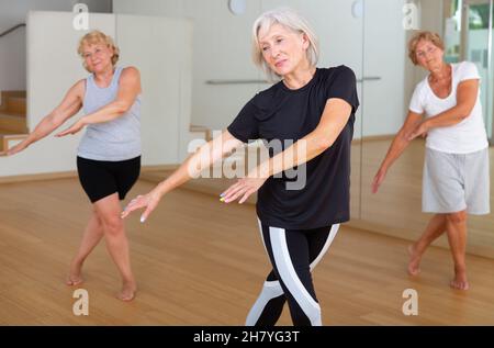 Positive aged woman practicing vigorous dance movements Stock Photo