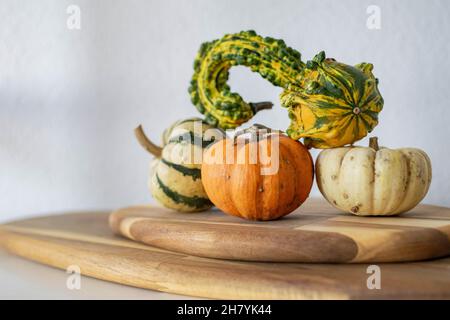 a selection of mini pumpkin decorations standing on a wooden chopping board Stock Photo