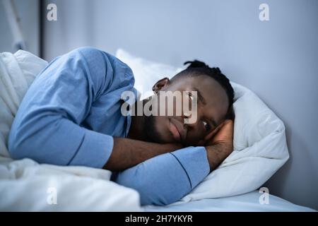 Young Man Suffering From Insomnia Lying In His Bed Stock Photo