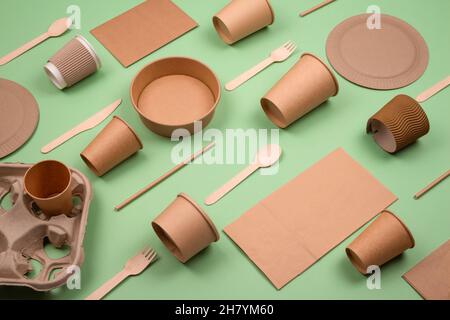 Set of different eco-friendly tableware and kraft paper food packaging on green background. Street food paper packaging - cups, plates, straws Stock Photo