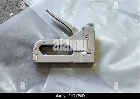 Stapler for repair and construction work, working tool close up, stapler lying on the floor. Stock Photo