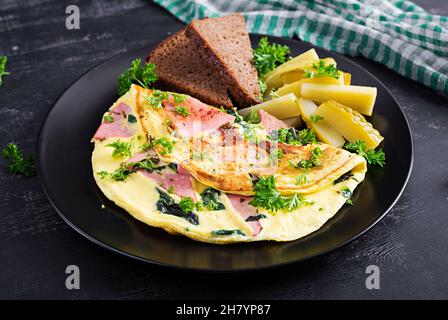 Omelet with boiled sausage and herbs, served with fermented cucumbers and bread. Rustic cuisine. Omelette. Stock Photo