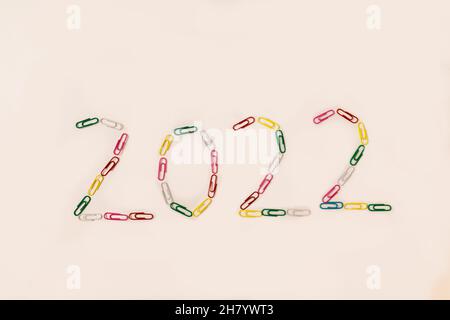 Number 2022 is laid out of multicolored paper clips on a white background.  Stock Photo