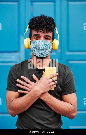 young man using smartphone and headphones outdoors in front of a door Stock Photo