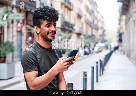 a young hipsanic man using his mobile phone outdoors in a cloudy day Stock Photo