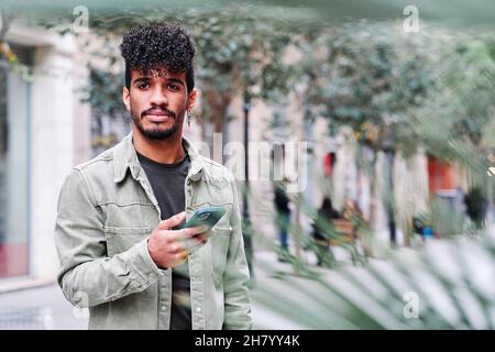 a young hipsanic man using his mobile phone outdoors in a cloudy day Stock Photo