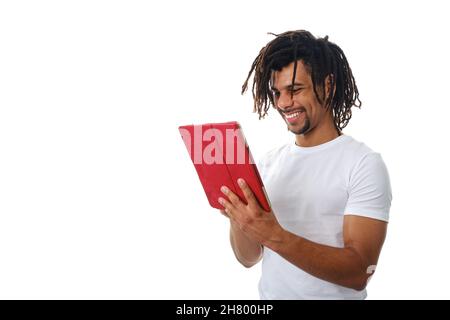 Latin man smiling while using a digital tablet over an isolated background. Stock Photo