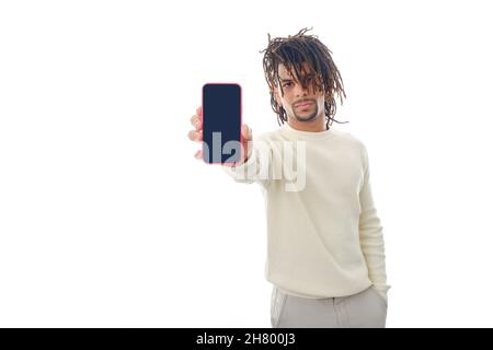Serious man showing blank screen mobile phone to camera while standing on isolated background. Stock Photo