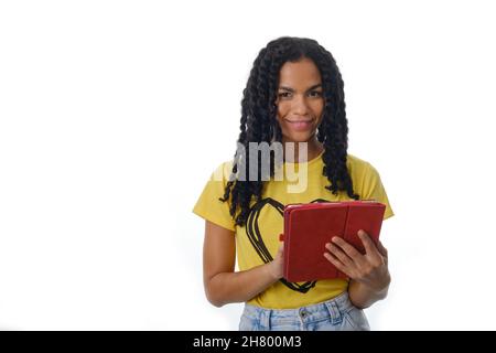 Smiling latin woman using a digital tablet while standing over an isolated background. Stock Photo