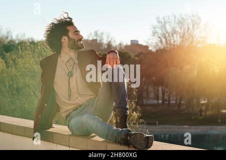 Man relaxed while sitting outdoors at park. Stock Photo