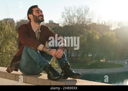Man smiling while sitting outdoors at park. Stock Photo