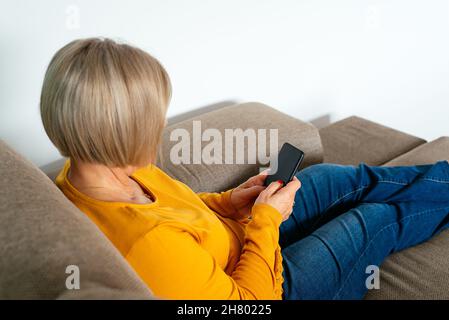 Adult female remote specialist in casual outfit discussing business issues during video conference via laptop while working in living room at home Stock Photo