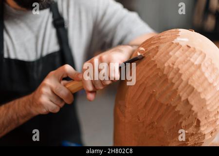 Anonymous carpenter shaping round wooden detail with professional chisel while working in joinery with special equipment Stock Photo