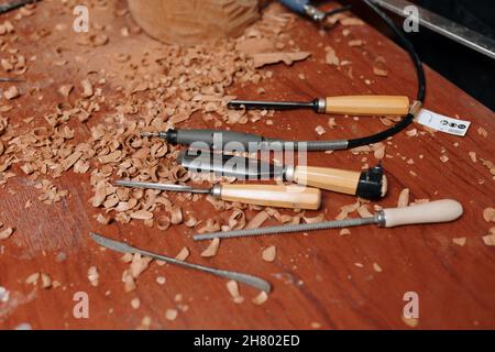 Collection of sharp chisels with wooden handles for carving wood placed on messy table with shavings in light modern joinery Stock Photo