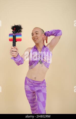 Happy non-binary person recording a video vlog or live streaming with a mobile phone. Stock Photo