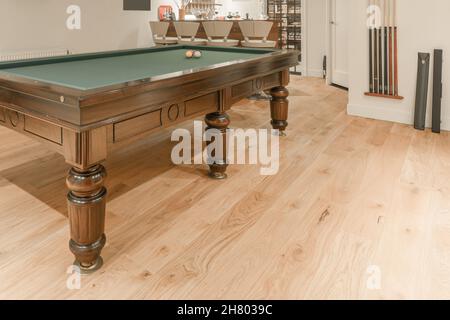 Interior of modern billiard room with pool table under chandeliers near relaxing area with sofa and tv on wall Stock Photo