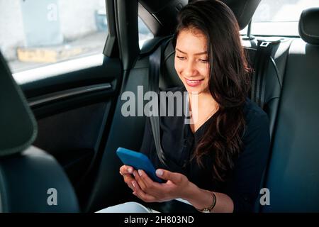 young latin businesswoman using smartphone in her car Stock Photo