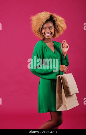 Cheerful afro woman holding brown paper shopping bags while standing over an isolated background. Stock Photo