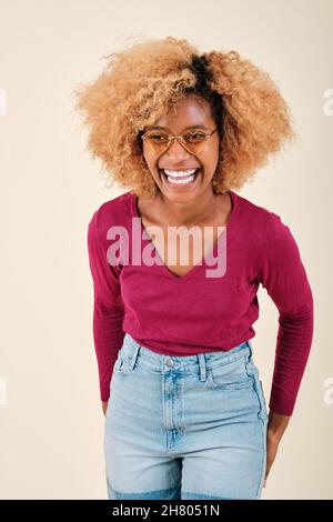 Happy and excited curly haired woman smiling while standing against an isolated background. Stock Photo