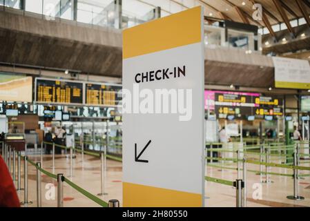 White check in direction board near counters with metal pillars in modern light public airport with flight schedule on contemporary signboards Stock Photo