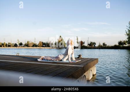 High angle of cropped unrecognizable young female freelancer messaging on mobile phone while sitting at table with laptop and cup of coffee in cozy ca Stock Photo