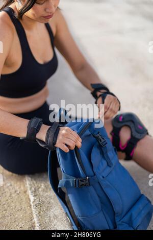 Side view of content male hiker with backpack sitting near lake in woods and browsing mobile phone while traveling Stock Photo
