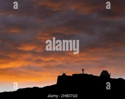 Amazing scenery of bright sunset sky with fluffy cumulus clouds over silhouette of rocky mountains in La Palma Island Stock Photo