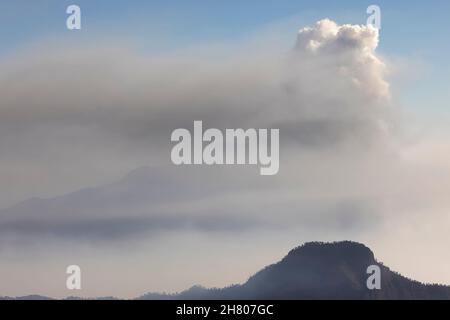 Picturesque scenery of fluffy white clouds floating in blue sky over mountains covered with trees in la Palma Island Stock Photo