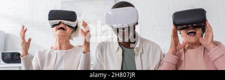 Positive multiethnic pensioners using vr headsets in nursing home, banner Stock Photo