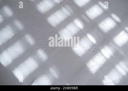 White gray plastered wall background. White concrete background close up. Abrasive white cement background in the rays of the sun with shadows Stock Photo