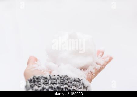 Snow hand close-up. A woman's hand in a gray sweater holds a lump of snow in the bright sunlight. The concept of cold winter snowfall, weather changes Stock Photo