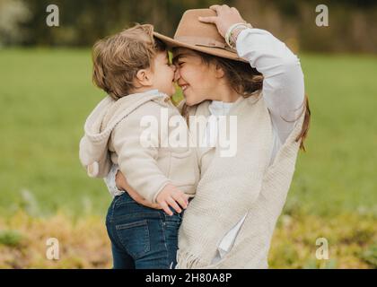 Happy mother embracing cute son and smiling together in park Stock Photo