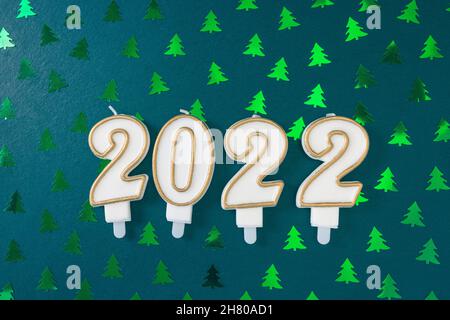 HAPPY NEW YEAR with 2022 candles on festive with Christmas tree foil confetti decoration background. Preparation and celebration concept. Flat lay, top view, copy space Stock Photo