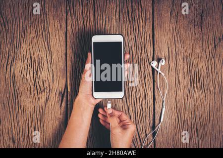 Top view hand charging phone on wood background Stock Photo
