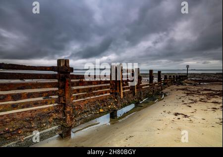 rusty old breakwater or groyne on a beach on the coastline of the isle of wight, atmospheric seascape with moody skies on isle of wight  shoreline. Stock Photo