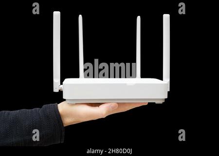 Male hand holding a modern dual band router against a black background. Upgrading to wi-fi 6. Stock Photo