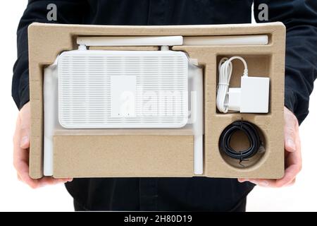 Man in black uniform showing a dual band Wi-Fi 6 router with accessories in a retail box. Stock Photo